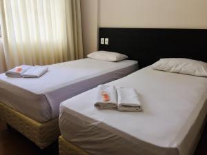 two beds in a hotel room with towels on them at Hotel GMatos Belo Horizonte - Próximo a Rodoviária e Mercados Turísticos in Belo Horizonte