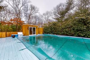 a swimming pool with a tiny house on a wooden deck at East Hampton Retreat in East Hampton