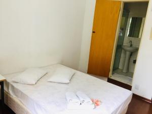 a bedroom with a bed with two white pillows and a sink at Hotel GMatos Belo Horizonte - Próximo a Rodoviária e Mercados Turísticos in Belo Horizonte