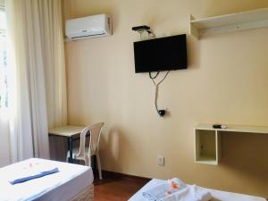 a room with two beds and a television on the wall at Hotel GMatos Belo Horizonte - Próximo a Rodoviária e Mercados Turísticos in Belo Horizonte