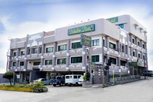 un grand bâtiment blanc avec des voitures garées devant lui dans l'établissement Paladin Hotel, à Baguio