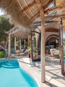 a resort with a swimming pool and a straw umbrella at Villa Amor in Sayulita