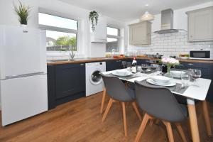 a kitchen with a table with chairs and a white refrigerator at Orion House - sleeps 6, driveway, garden in Crewe