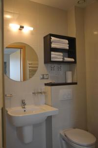 a bathroom with a sink and a toilet and a mirror at Restauracja 32 Motel in Gryfice