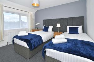 a bedroom with two beds with blue and white sheets at Orion House - sleeps 6, driveway, garden in Crewe