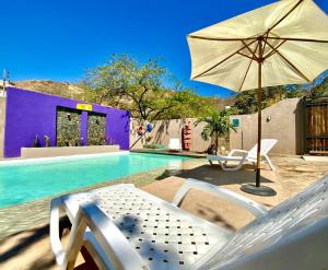 譚岡加的住宿－Hostal Aurora, Smith Lodging，一个带椅子和遮阳伞的游泳池以及一个游泳池