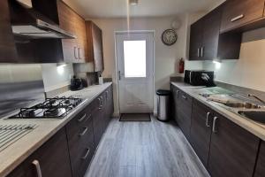 a kitchen with wooden cabinets and a stove top oven at The Moorings, 2 bed apartment with private garden. in Anstruther