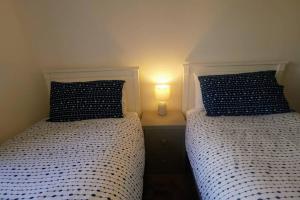 2 Betten in einem Schlafzimmer mit einer Lampe auf einem Tisch in der Unterkunft The Moorings, 2 bed apartment with private garden. in Anstruther