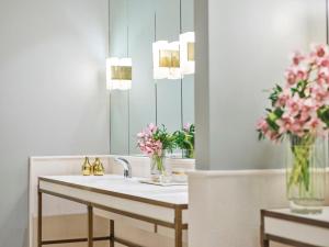 a bathroom with a sink and a vase of pink flowers at The Beverly Hills Hotel - Dorchester Collection in Los Angeles