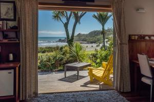a living room with a view of the beach from a door at Hydrangea Cottages in Punakaiki