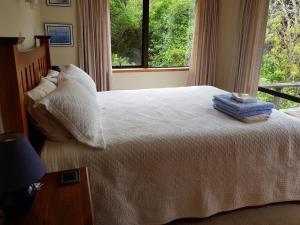 a bedroom with a white bed with a window at Awesome View Cottage in Great Barrier Island