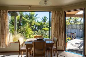 a dining room with a table and chairs and a large window at Hydrangea Cottages in Punakaiki