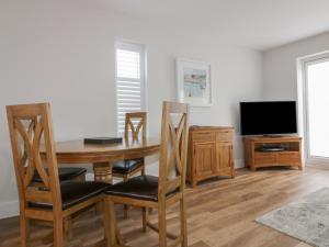 a dining room with a table and chairs and a television at The Sand Dunes in Crantock