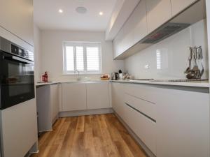 a kitchen with white cabinets and a wooden floor at The Sand Dunes in Crantock +13 photos