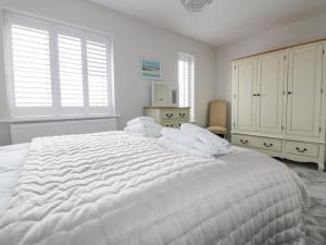 a white bedroom with a large white bed with white pillows at The Sand Dunes in Crantock