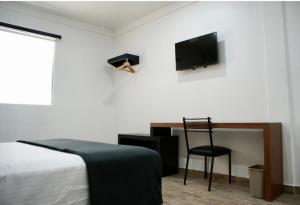 - une chambre avec un lit, une chaise et une télévision dans l'établissement Hotel Capital Frontera, à Monclova