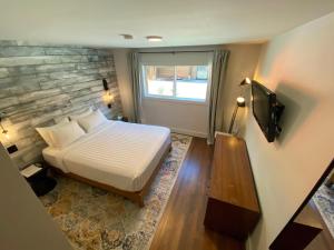 1 dormitorio con 1 cama y TV en The Maq Hotel, en Tofino