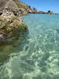 a body of water next to a rocky beach at CASA PÔR DO SOL 1 in Arraial do Cabo
