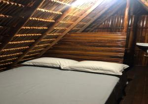 a bed in a room with a wooden wall at Cabana Camping Jalapão in São Félix do Tocantins