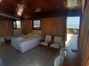 a bedroom with a bed and chairs and a balcony at Pousada Mirante do Pontal in Coruripe