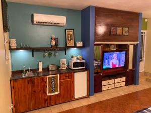 a living room with a kitchen with a tv and a counter at Family Guest House in Quebradillas
