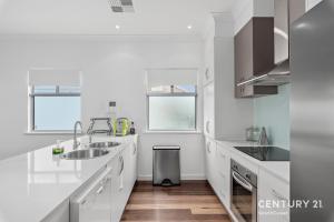 a white kitchen with two sinks and a trash can at Percival Point - Port Willunga - C21 SouthCoast Holidays in Port Willunga