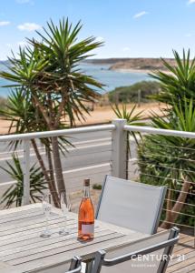 a bottle of wine sitting on a table with glasses at Percival Point - Port Willunga - C21 SouthCoast Holidays in Port Willunga