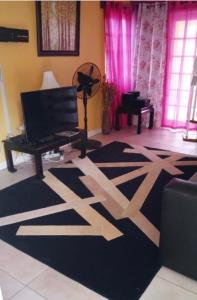 a living room with a black and white rug and a piano at Poolside Mystic Apt 9A in Ocho Rios