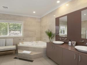 a bathroom with two sinks and a bath tub and a tubermott at Hillview Cottage in Bowral