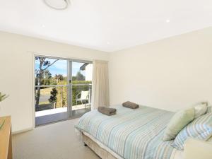- une chambre blanche avec un lit et une grande fenêtre dans l'établissement Isthmus on North Kiama Drive, à Kiama Downs