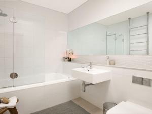 a white bathroom with a sink and a bath tub at The Gullies Retreat in Bundanoon