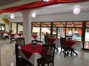 a restaurant with red tables and chairs and windows at Coco Beach Hotel in Coco