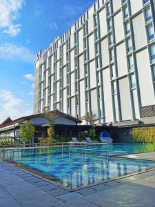a hotel with a swimming pool in front of a building at Swiss-Belinn Saripetojo Solo in Solo