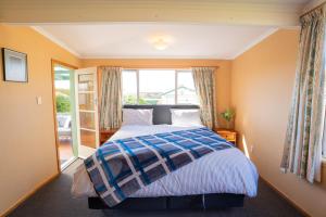 a bedroom with a bed and a large window at Dee's on Bligh - Te Anau Holiday Home in Te Anau