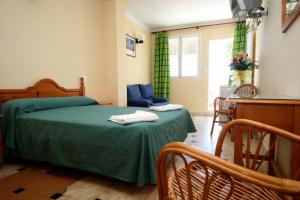 a bedroom with a green bed with two towels on it at Hotel Playa in Mojácar