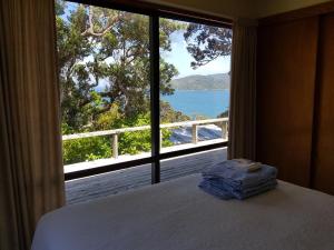 una camera da letto con una grande finestra con vista sull'oceano di Awesome View Cottage a Great Barrier Island