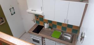 a small kitchen with white cabinets and green and orange tiles at studio de jack in Le Mesnil-Esnard
