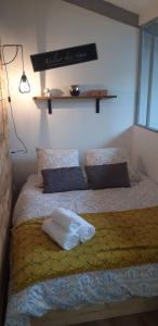 una cama con una almohada blanca encima en studio de jack en Le Mesnil-Esnard