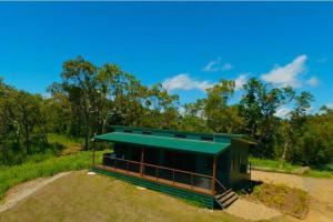 a small building with a green roof on a field at Ridge Cabin - Stunning Views - 5km From Neighbours in Airlie Beach