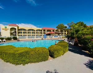 a resort with a large pool in front of a building at Quality Inn Airport East in El Paso