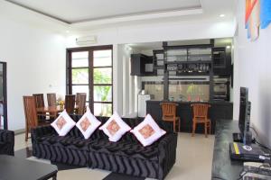 a living room with a black couch with pink pillows at Ketut Villa Sanur in Sanur