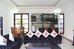 a living room with a black couch with pillows on it at Ketut Villa Sanur in Sanur
