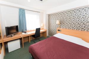 a hotel room with a bed and a desk with a television at Hotel Ark 21 in Kurayoshi