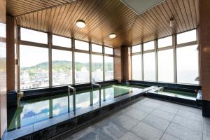 a swimming pool in a building with windows at Hotel Ark 21 in Kurayoshi