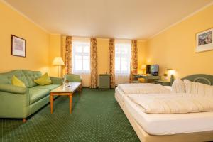 a hotel room with two beds and a couch at Hotel Herzog Georg in Bad Liebenstein
