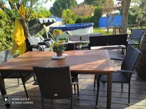 una mesa de madera y sillas en un patio en Abrivado Appartements meublés dans une grande propriété en rez de jardin en Aimargues