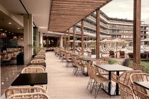ein Restaurant mit Tischen und Stühlen und ein Gebäude in der Unterkunft Sunny Beach Club - Adults Only in Sonnenstrand