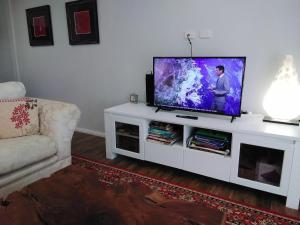 a living room with a flat screen tv on a white entertainment center at Keillor Lodge in Maleny