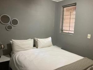 a bedroom with a bed with white sheets and a window at Guesthouse @ 31 Murray in Pretoria