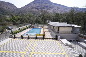 a swimming pool on top of a building with a mountain at Indradhanush Hill Resort in Mulshi